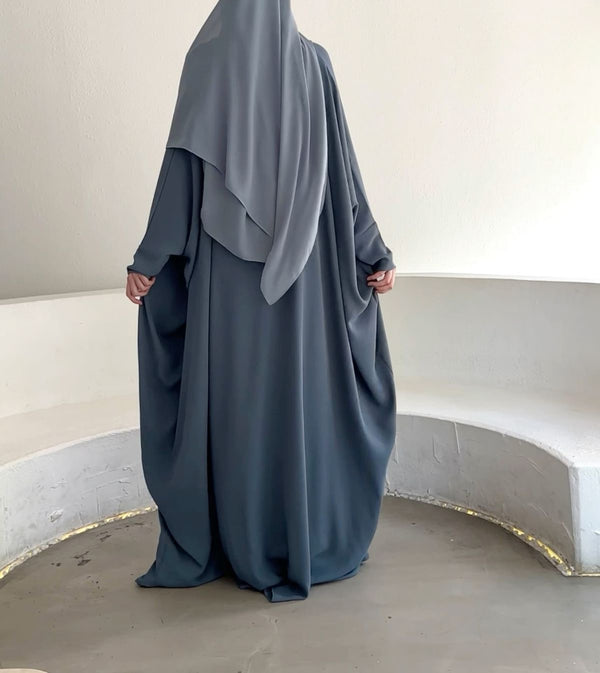 A woman wearing a sky blue flowy abaya, standing gracefully with a serene and modest look
Sky Blue Elegant Abaya for Women | Modern Modest Fashion