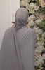 Back view of a grey abaya and khimar set featuring crystal embellishments, worn by a model in front of a floral background